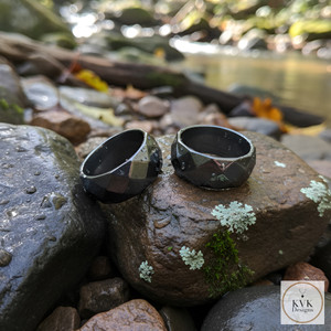 6mm Faceted Hematite Rings sitting on rocks outside