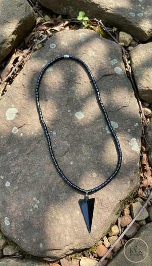 Arrow Head Hematite Necklace laying on rocks outside