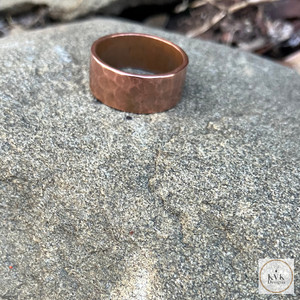 8mm Hammered Copper Band Ring sitting on a stone