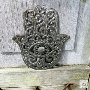 Unique Handcrafted Hamsa Hand Metal Art sitting on a piece of wood Unique Handcrafted Hamsa Hand Metal Art sitting on a piece of wood