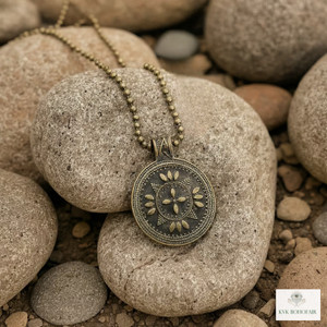 Round Bronze Tribal Pendant Necklace sitting on rocks Round Bronze Tribal Pendant Necklace sitting on rocks