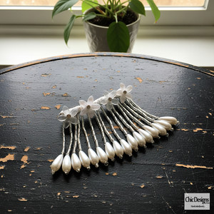 Rhinestone and Resin Flowered Fringe with Pearl Accented Hairpin sitting on a black antique distressed table Rhinestone and Resin Flowered Fringe with Pearl Accented Hairpin sitting on a black antique distressed table