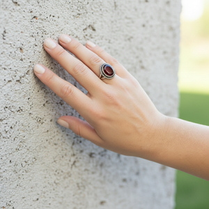 Faceted Garnet Ring with Rope Edge worn by model leaning against a stone wall Faceted Garnet Ring with Rope Edge worn by model leaning against a stone wall