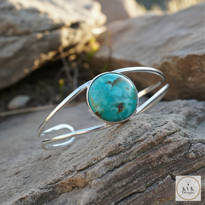 Open Band Cuff with Turquoise sitting on a rock outside