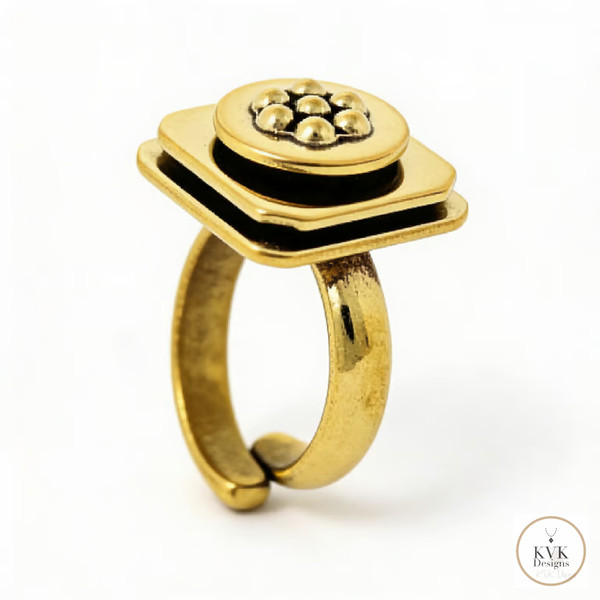 A gold ring with a geometric, layered square design topped with a cluster of small gold spheres in a flower design. The ring has an adjustable, open-ended band and features the KVK Designs logo in the bottom right corner.