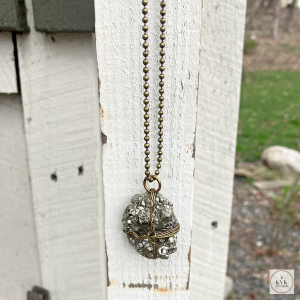 Pyrite Wire-Wrapped Necklace hanging from a wood post