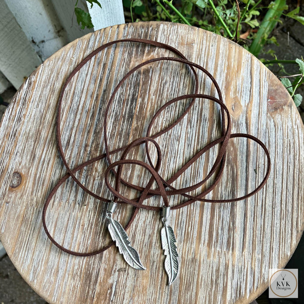 Boho Chic: Brown Suede Lariat Feather Necklace on a wood table