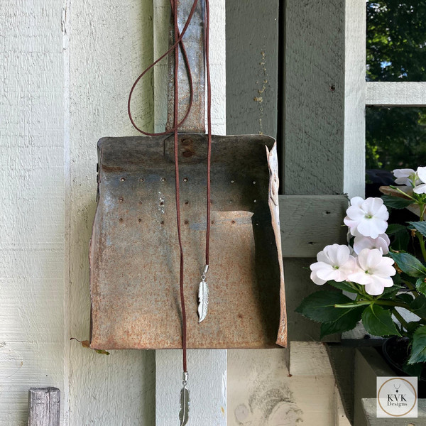 Boho Chic: Brown Suede Lariat Feather Necklace hanging from an antique shovel