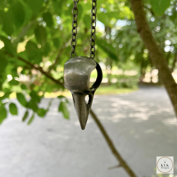 Silver Crow Skull Necklace Pendant hanging outside from a tree branch