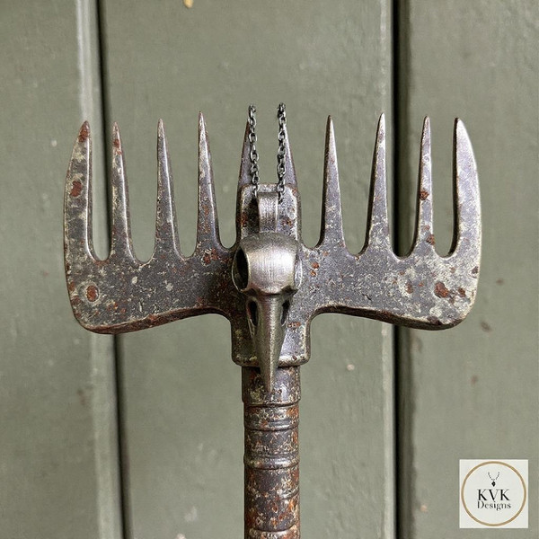 Silver Crow Skull Necklace Pendant hanging from an old rake