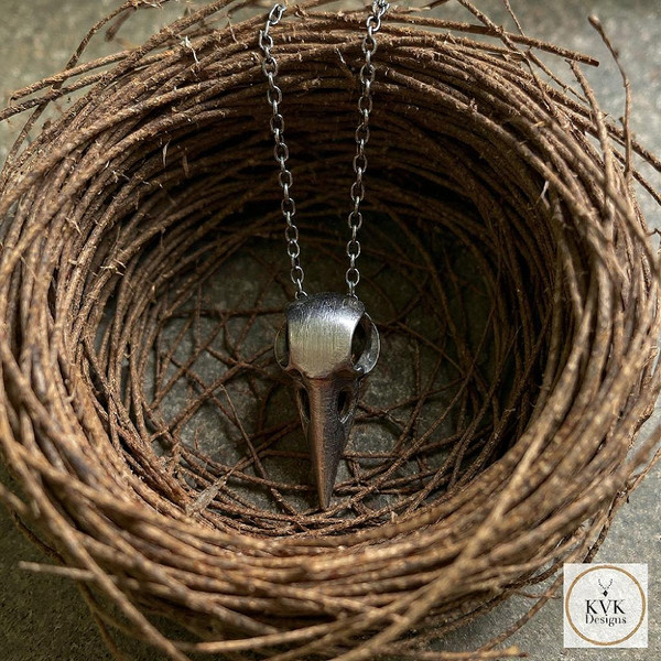 Silver Crow Skull Necklace Pendant sitting in a birds nest