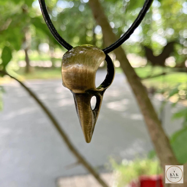 Brass Crow Skull Necklace Pendant hanging outside on a tree branch
