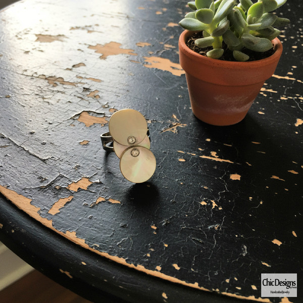 Blue/Gray Mother of Pearl Three Circular Ring Accented with Swarovski Rhinestones on a black distressed table with plant