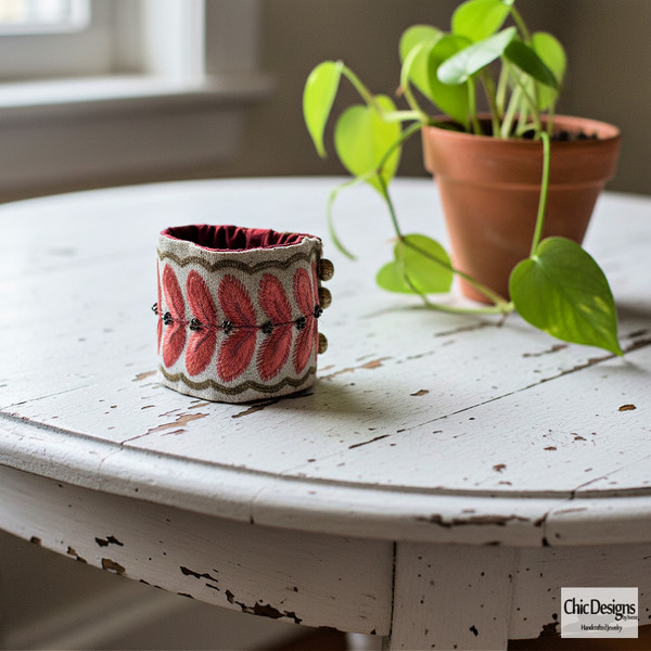 Ravishing Red/Pink Embroidered Leaf Cuff & Flower on distressed white table with a plant