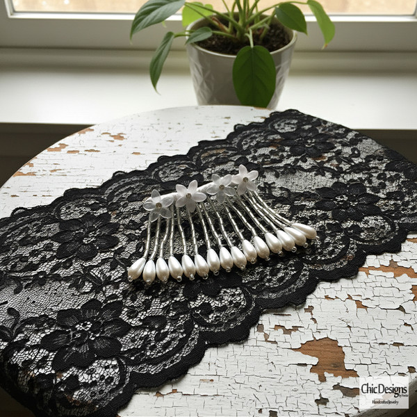 Rhinestone and Resin Flowered Fringe with Pearl Accented Hairpin sitting on a piece of black lace on a white distressed table