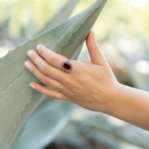 Faceted Garnet Ring with Rope Edge worn by model holding onto a cactus leaf