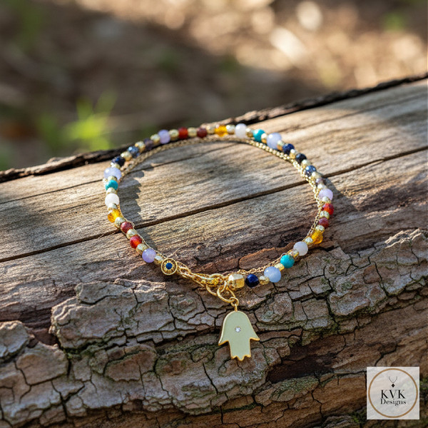 Double Strand Gemstone Hamsa Hand Charm Bracelet sitting on log outside