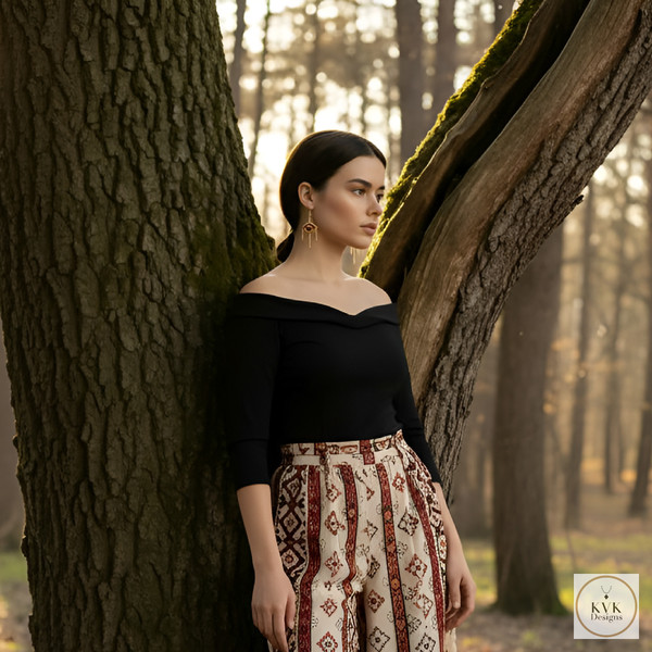 A woman wearing a black off-shoulder top and patterned skirt stands next to a tree in a sunlit forest, looking thoughtfully into the distance. A woman wearing a black off-shoulder top and patterned skirt stands next to a tree in a sunlit forest, looking thoughtfully into the distance.