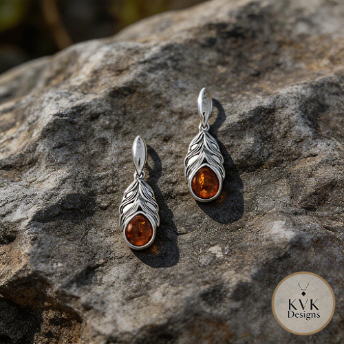 Oxidized Amber Feather Earrings laying on rocks outside