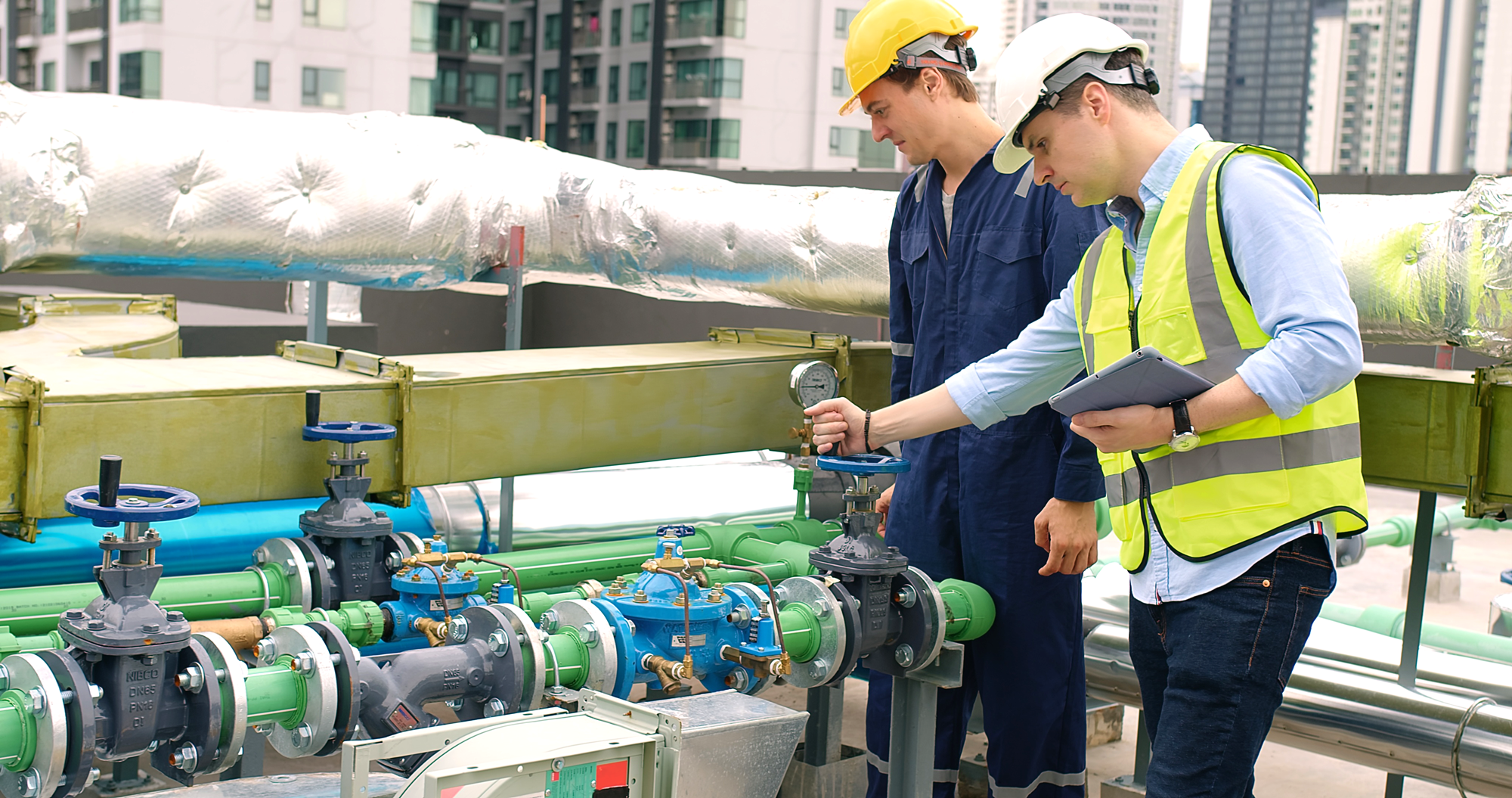 Technicians performing onsite testing of valves and pressure gauges in an industrial gas or fluid distribution system.
