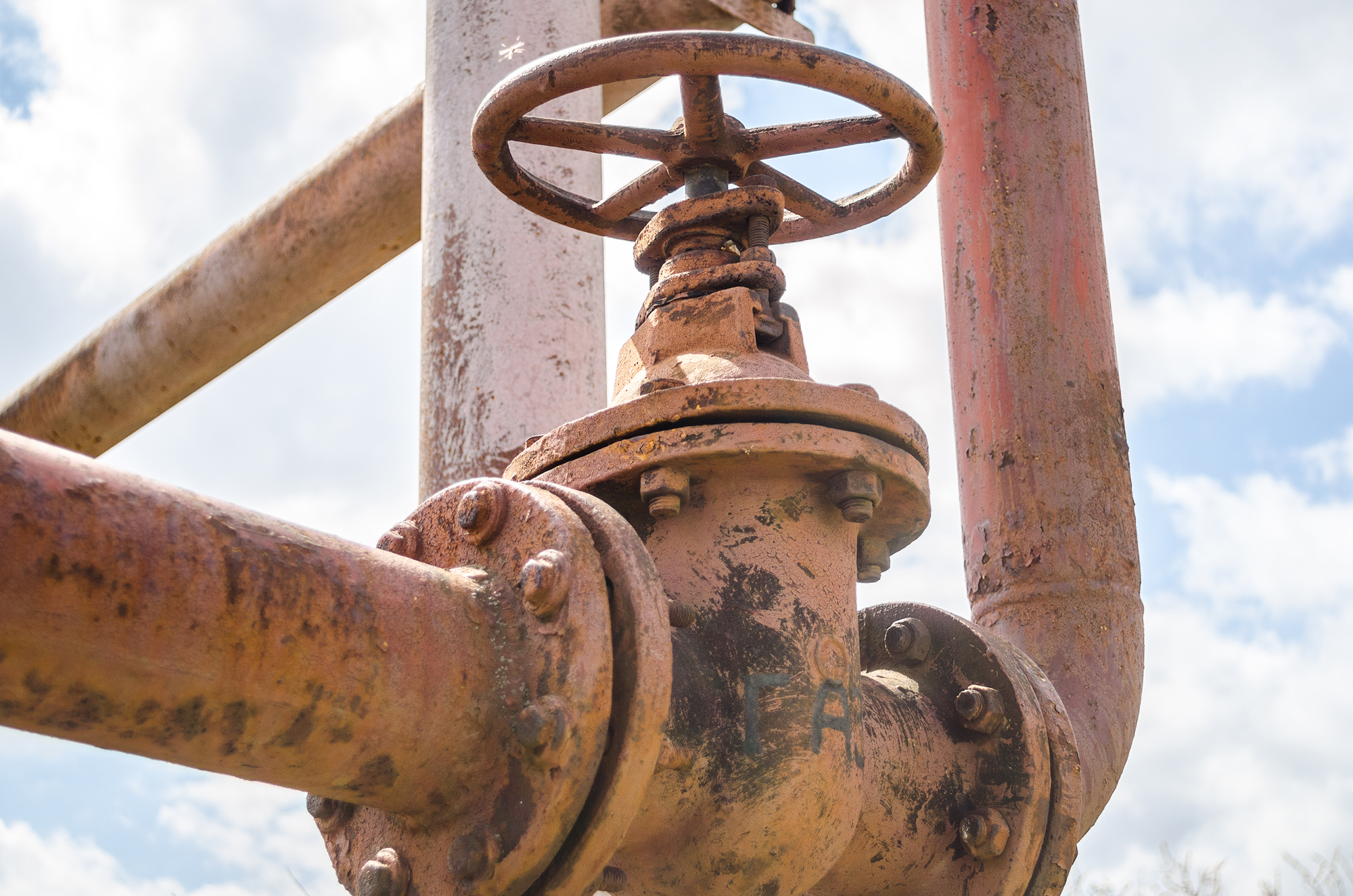 Corroded industrial pipeline valve with manual handwheel for flow control in a gas pipeline system.