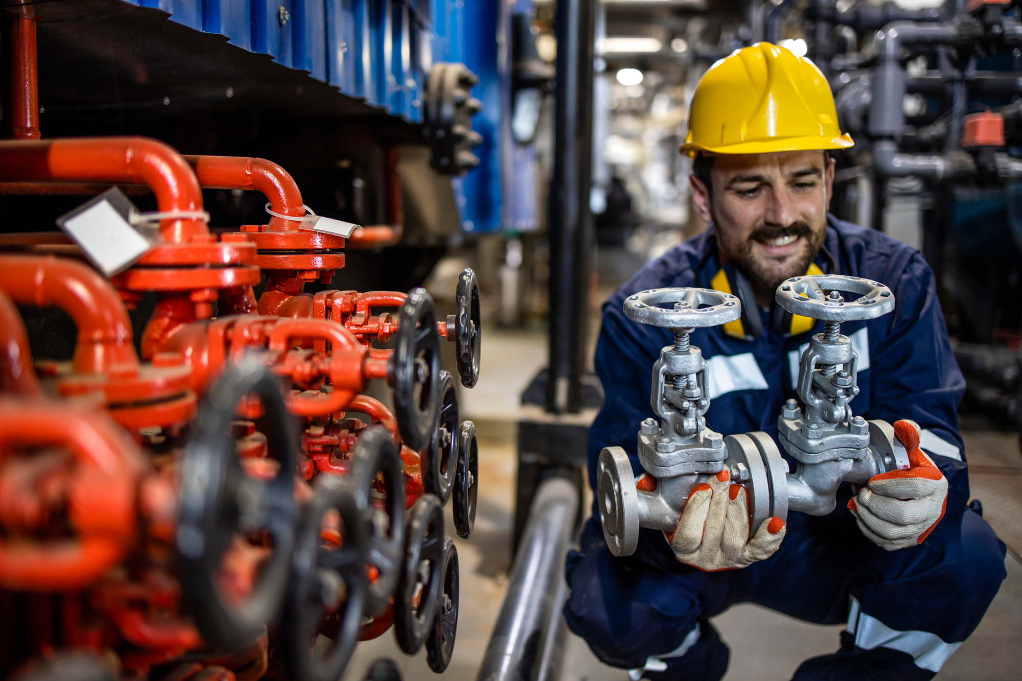 Industrial technician inspecting pipeline valves in a gas processing system.