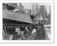 Army tanks on barge in icy water, N.Y. harbor; skyscrapers in background, Vintage Poster