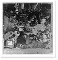 Mounted animals: Taxidermist in chair with eyes closed in room full of mounted animals and birds, Vintage Print