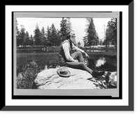 John Muir, full-length portrait, facing right, seated on rock with lake and trees in background, Historic Reproduction