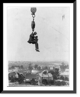 Photographer with camera suspended from hook of a (crane?) high in the air, Vintage Print