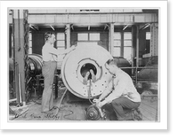 Three men working on large gun in Naval Gun Factory, Washington, D.C.; one of the men lying in the barrel, Historic Reproduction