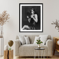 Barbara Stanwyck, three-quarter length portrait, seated, turned to the left, holding fan, Historic Reproduction
