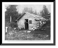 Man with shotgun at doorway of cabin and a deer hanging from pole at camp, Eighth Lake, Fulton Chain, Adirondack Mountains, N.Y, Historic Print