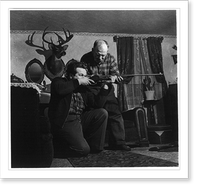 Andrew Scavnicky with his son Paul, who is aiming rifle, in livingroom, Hazelton, Pa. Behind them hangs the head of a deer with large antlers, which Paul shot, Vintage Wall Art
