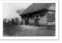 Baskets in front doorway of Polish cottage, with 2 children seated on right and man standing to left, Vintage Print
