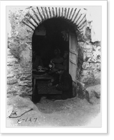 View through doorway of home in Salonika, Greece, showing family dining as boy of the house picks out nut meats in foreground, Vintage Print