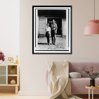 Historic Framed Print, [Charles Lindbergh and Anne Morrow Lindbergh, full-length portrait, standing in front of cabin on Etarofu Island, Russia],  17-7/8" x 21-7/8"