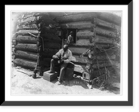 Historic Framed Print, [Afro-American man seated outside log cabin, pouring drink into cup and girl seated in window of the cabin],  17-7/8" x 21-7/8"