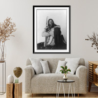 Distributor, Native American man, three-quarter length portrait, seated, facing right; arms folded, holding bow, arrow, and tomahawk; dressed in bone breast plate, Antique Wall Art