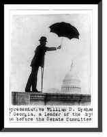 Historic Framed Print, [Representative William D. Upshaw of Georgia, a leader of the drys, standing on railing with crutch and holding umbrella, with dome of the U.S. Capitol under the umbrella,  17-7/8" x 21-7/8"