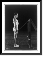Historic Framed Print, [Gene Tunney, full-length portrait, standing, right profile, lifting weights on pulleys],  17-7/8" x 21-7/8"