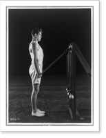 Historic Framed Print, [Gene Tunney, full-length portrait, standing, right profile, lifting weights on pulleys],  17-7/8" x 21-7/8"