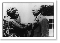 Florence Harding pinning flower on lapel of President Warren Harding in a garden, half-length portraits, standing, Antique Poster