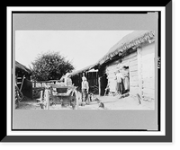 Two women standing in yard and other women and children standing in doorway of log structure, Russia - 2 Classic, Vintage Poster