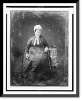 Unidentified woman, about 60 years of age, full-length portrait, facing front, seated beside small table with tablecloth and handbag, wearing white cap, Vintage Poster