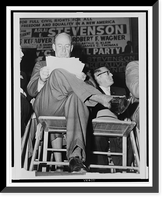 Adlai E. Stevenson, full-length portrait, seated, facing front, studying his speech notes, at a campaign rally in the Harlem section of New York City, Vintage Poster