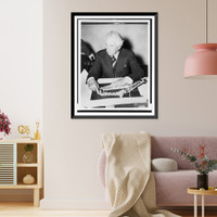 Historic Framed Print, [Frank Lloyd Wright, half-length portrait, seated, facing slightly left, pointing to his design for Crystal Heights].Harris & Ewing.,  17-7/8" x 21-7/8"
