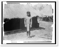 Historic Framed Print, [Young man in traditional clothes beside thatch-roofed structure in Igorot village, Louisiana Purchase Exposition],  17-7/8" x 21-7/8"