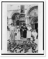 Vincent Price and three women holding pigeons, surrounded by flock of pigeons, outside a building in Italy, Historic Print