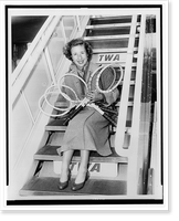 Maureen Connolly holding five tennis rackets while she sits on the boarding steps of airplane, Vintage Print